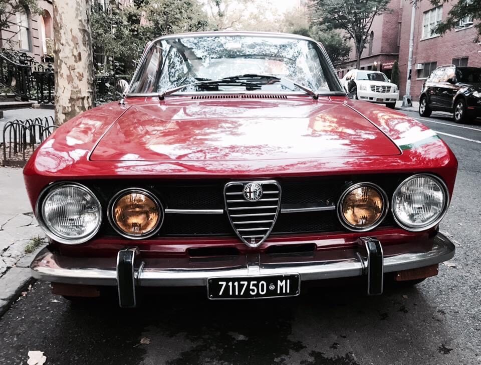 Red Alfa Romeo GTV, head-on front view on a tree-lined city street