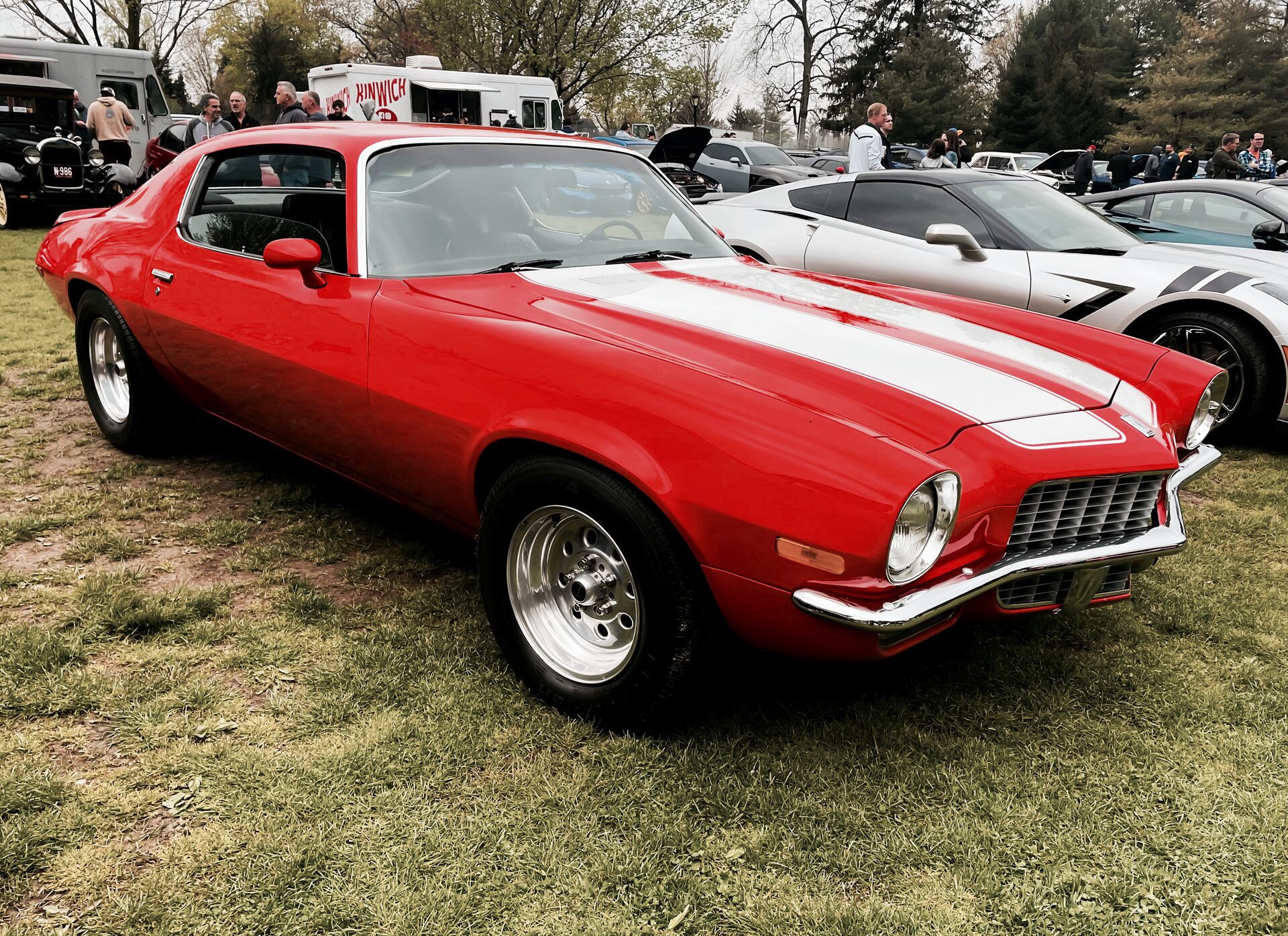 Red Chevrolet Camaro Z/28 with white stripes, three-quarter front view at a car show