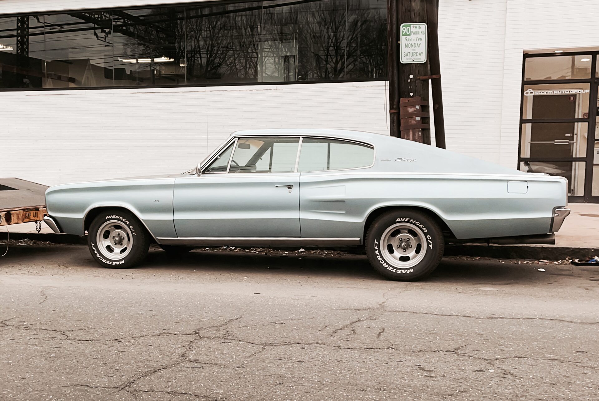 Light blue Dodge Charger in side profile, parked outside an auto-body shop