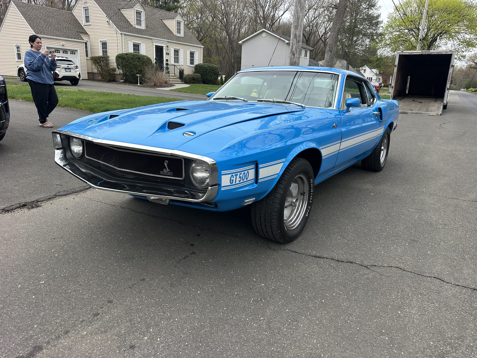Grabber-blue Shelby GT500 with white side stripes, three-quarter front view in a suburban driveway