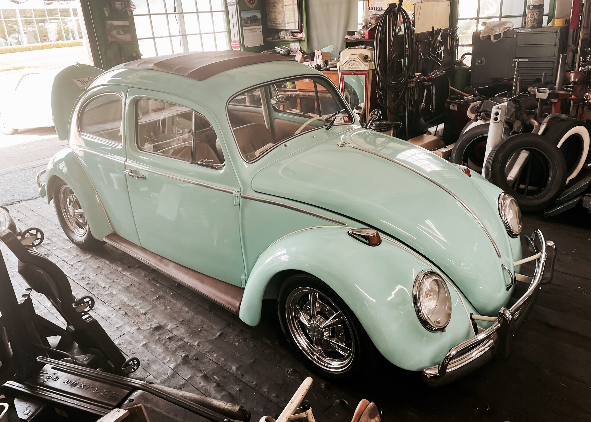Mint green Volkswagen Beetle parked inside an old workshop garage
