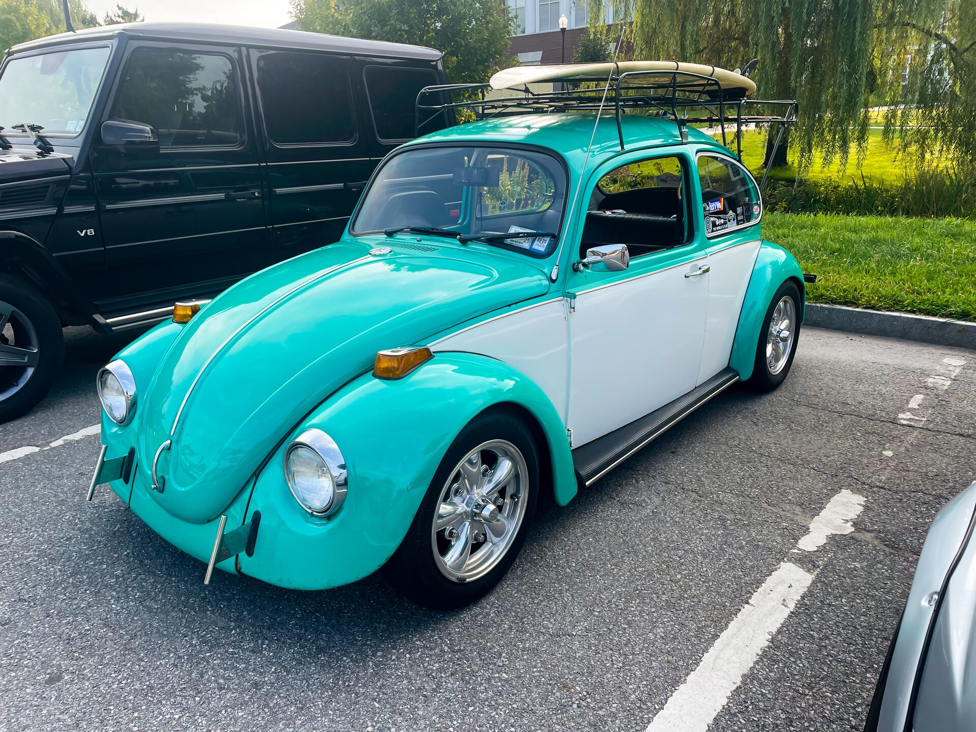 Turquoise and white Volkswagen Beetle with roof-rack surfboard, three-quarter front view