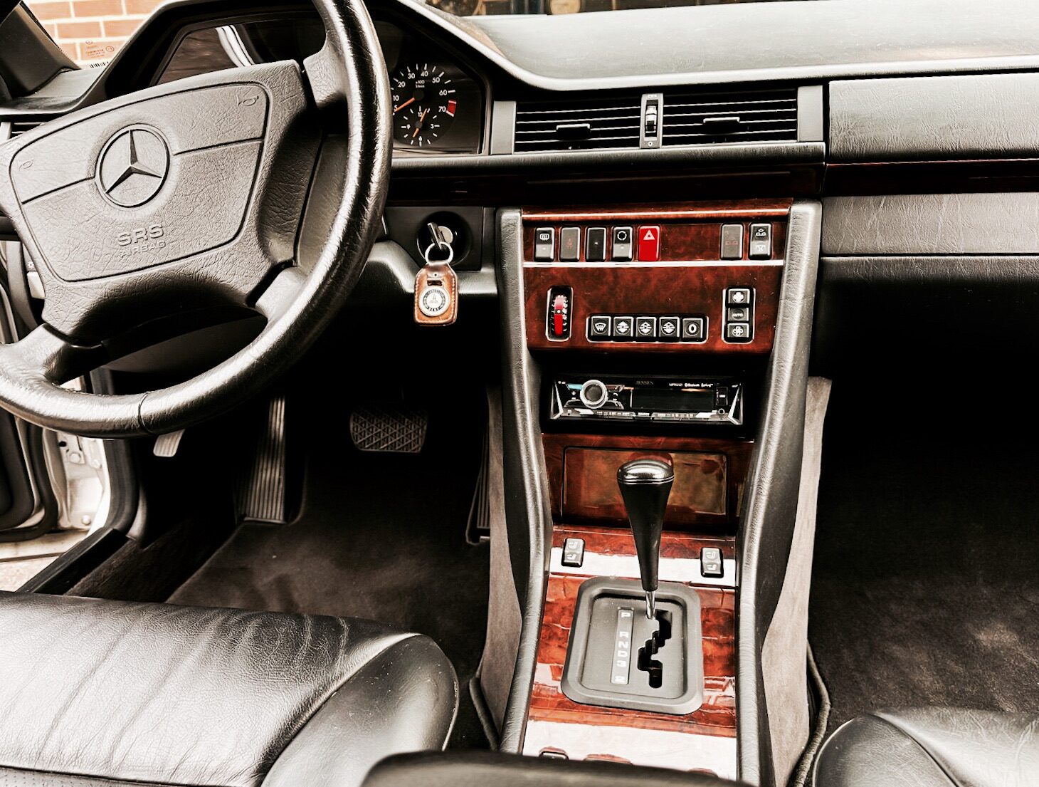 Dashboard and center console of the 1995 Mercedes E320 Cabriolet &mdash; wood trim, automatic shifter, factory radio replaced with aftermarket head unit