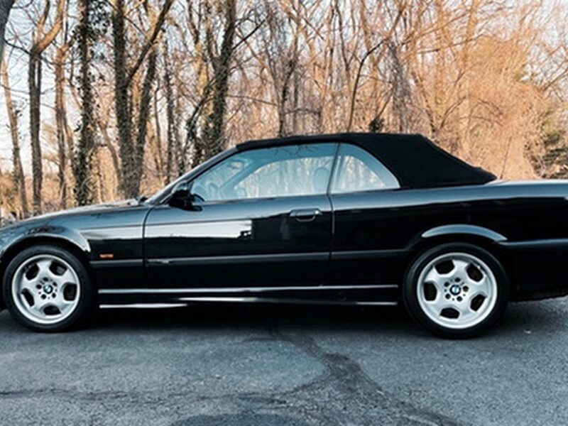 1998 BMW M3 Convertible (E36) in black, parked on a wooded drive